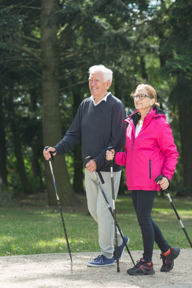 Elderly couple walking with nordic walking/trekking poles